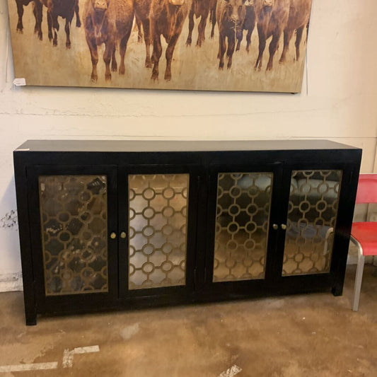 Black cabinet with decorative glass panels in a room with a painting of animals on the wall.
