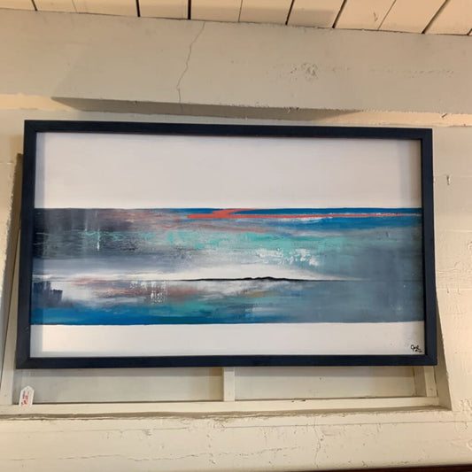 Framed abstract painting with blue and white brushstrokes on a light gray wall.