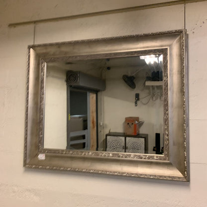 Decorative silver-framed mirror on a wall