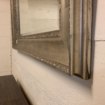 Decorative mirror with ornate frame on a textured wall