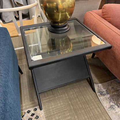 Small black side table with glass top in a room setting