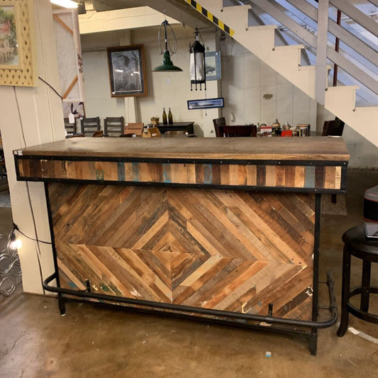 Wooden bar with a chevron pattern and metal frame in a room with stairs and decor.