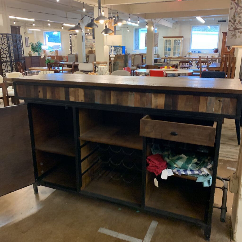 Wooden kitchen island with storage shelves and a drawer in a showroom setting.