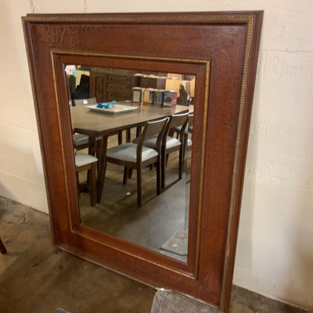 Wooden-framed mirror reflecting a dining room setting