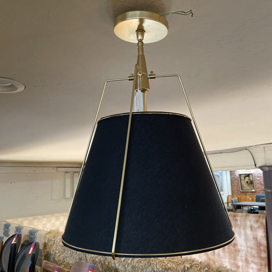 Pendant light with black shade and gold fixture in a room setting