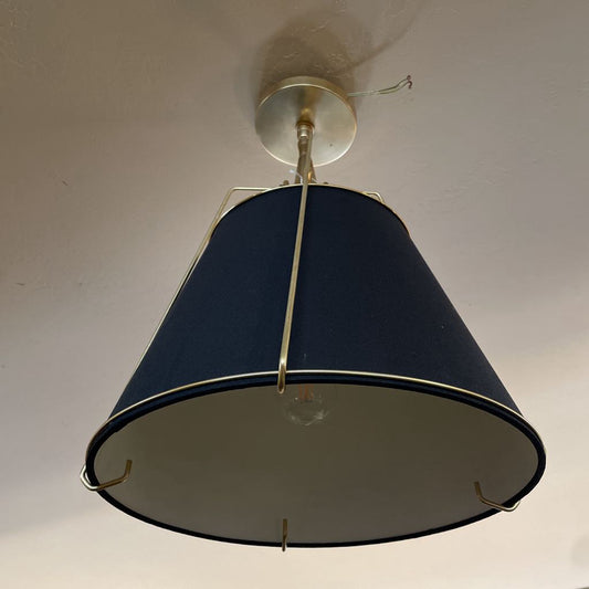 Ceiling light fixture with a dark blue shade and brass fitting on a plain wall.