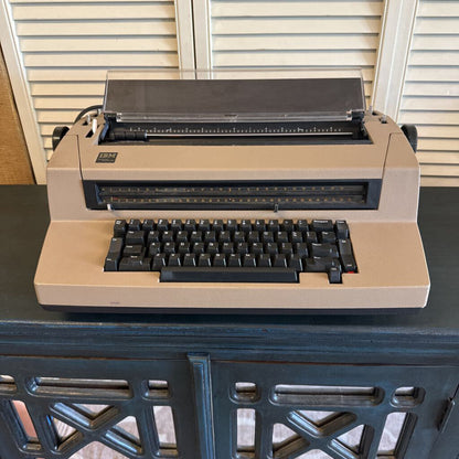 Beige typewriter on a dark surface with a neutral background