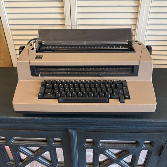 Beige typewriter on a dark surface with a neutral background