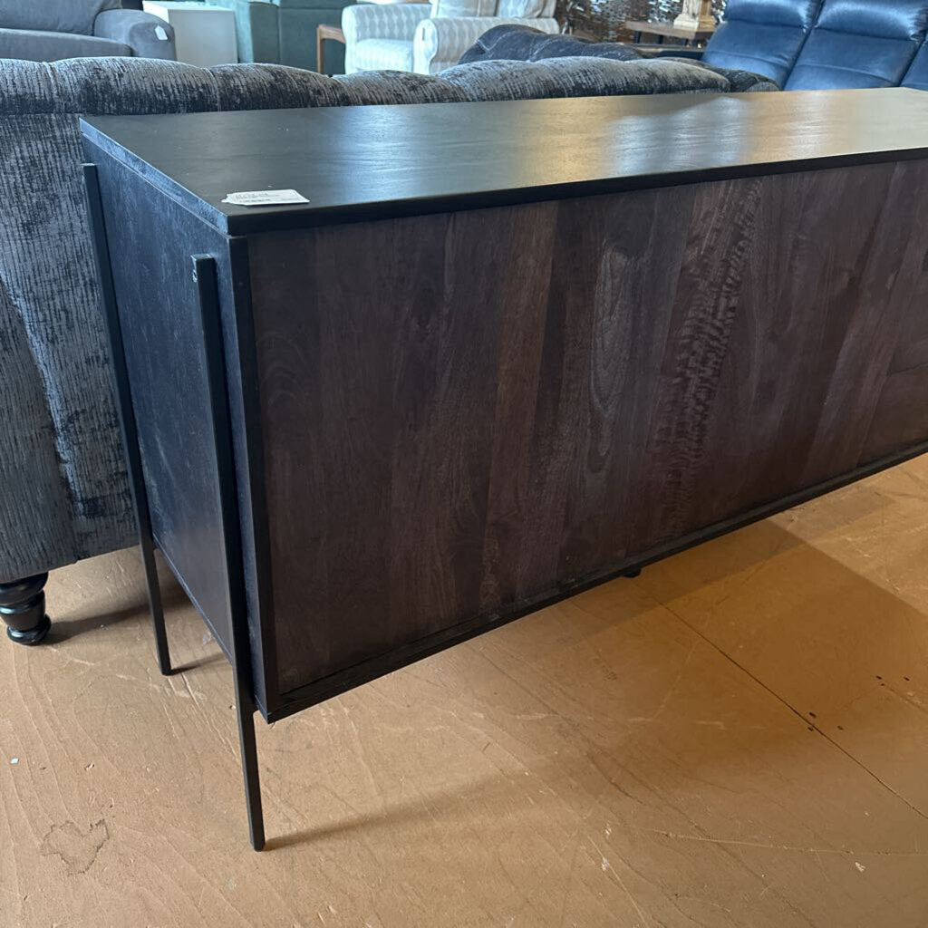 Dark wood console table on a wooden floor with furniture in the background