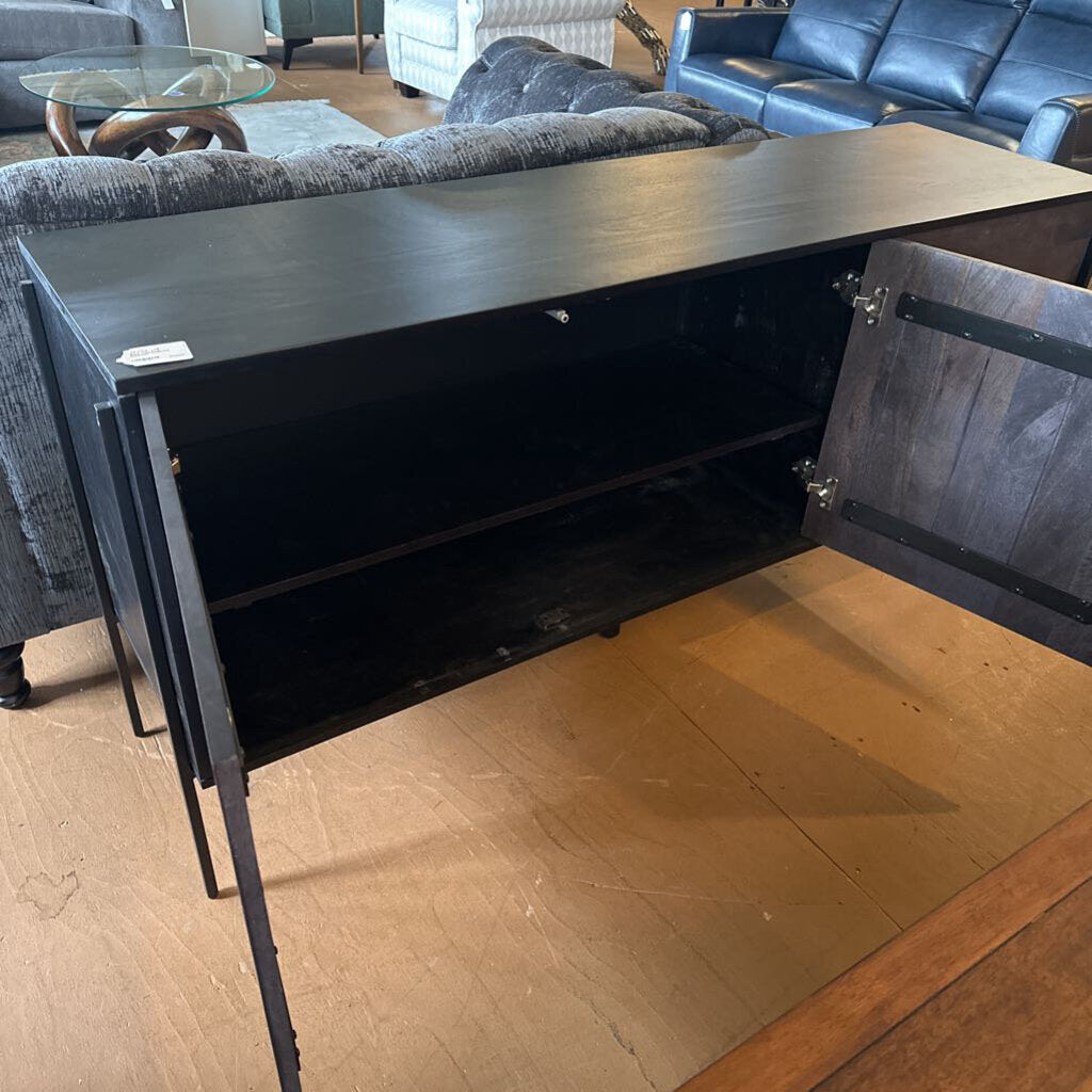 Black metal console table with open door in a living room setting