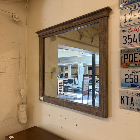 Wooden-framed mirror on a wall with license plates below