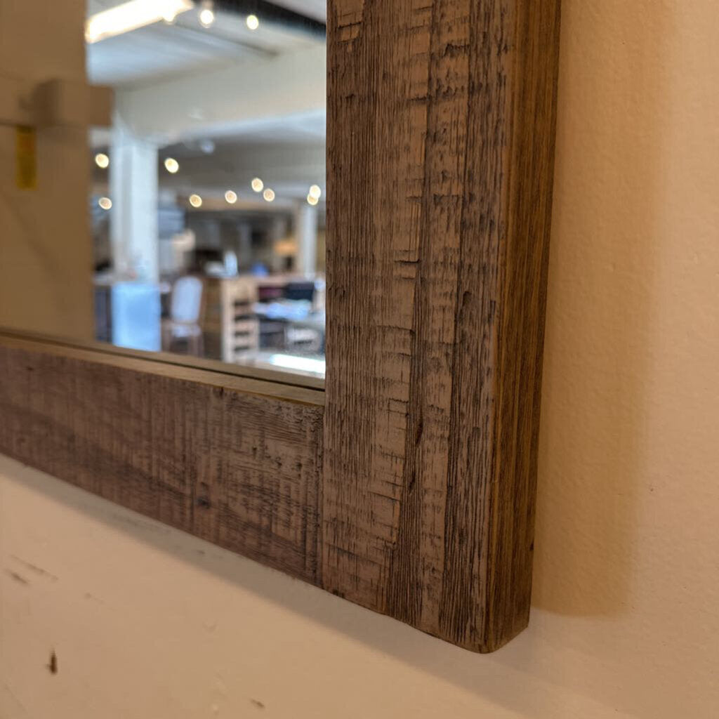 Wooden-framed mirror on a wall with blurred interior background