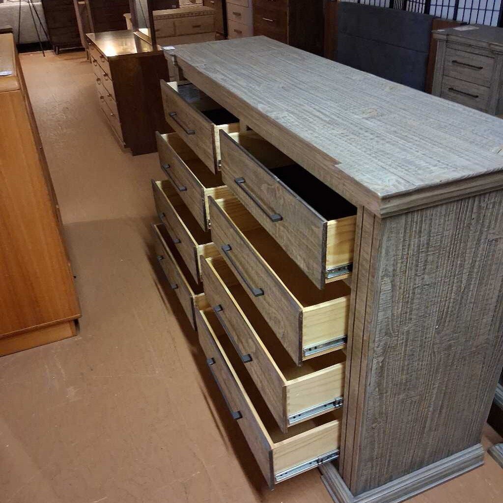 Wooden dresser with multiple drawers in a furniture store setting