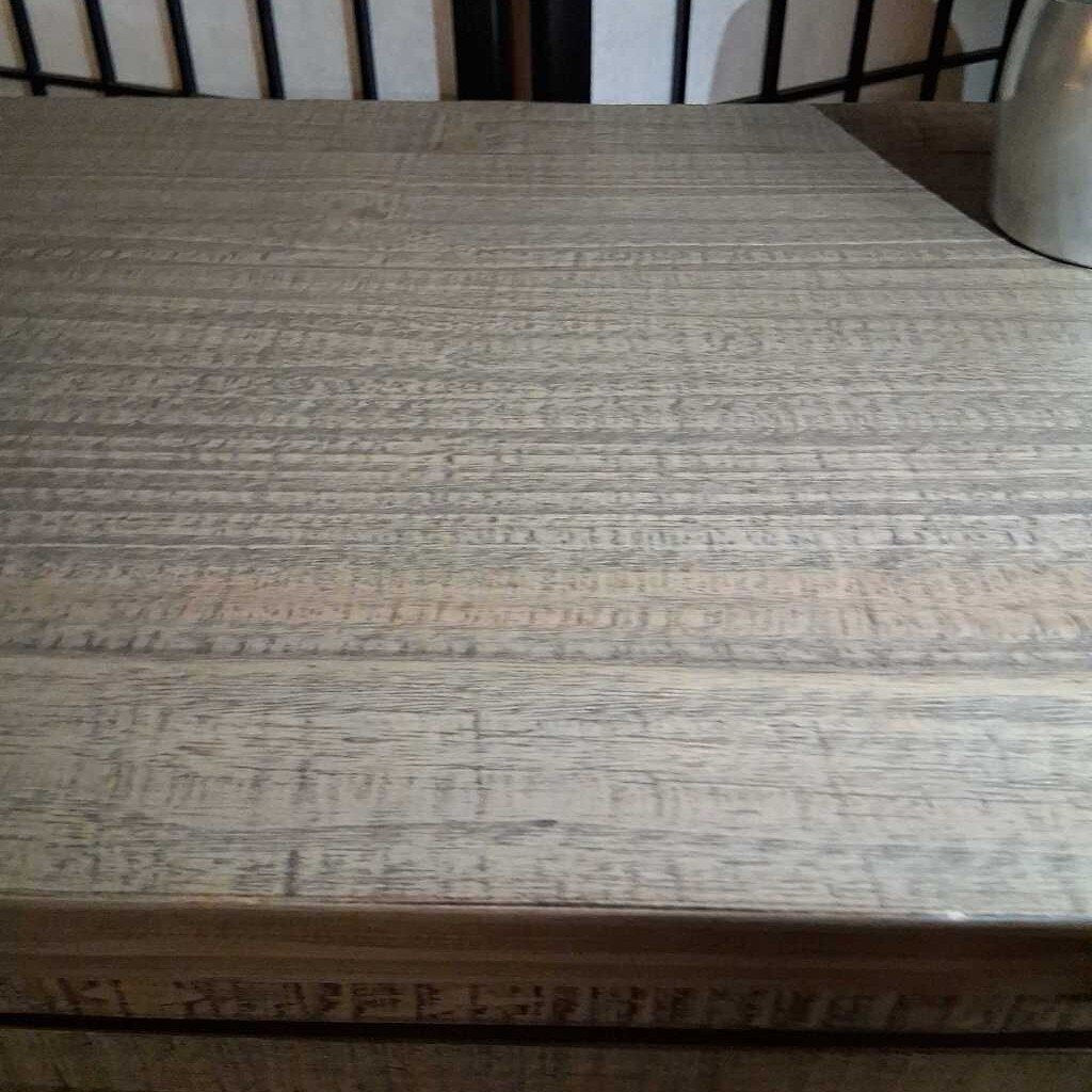 Textured surface of a wooden table with a black and white striped pattern in the background.