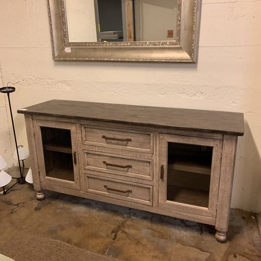 Wooden console table with glass doors and drawers in a room setting.