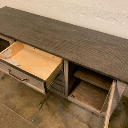 Wooden console table with an open drawer against a white wall.