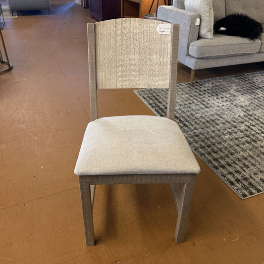 Gray chair with beige cushion on a wooden floor in a room setting