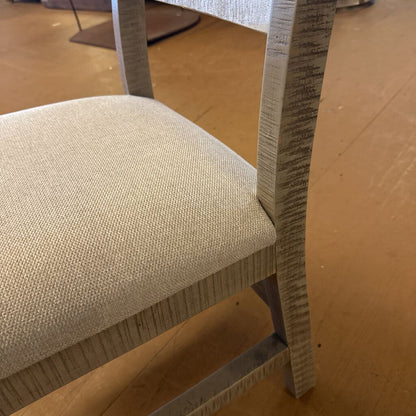 Close-up of a chair with a textured seat and backrest on a wooden floor.