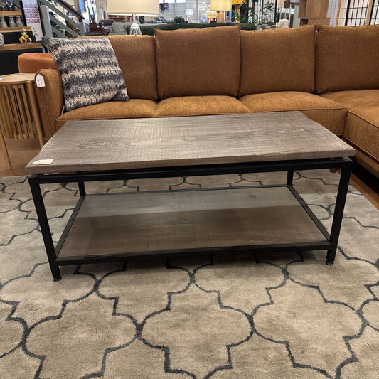 Brown sectional sofa with a coffee table on a patterned rug in a store setting