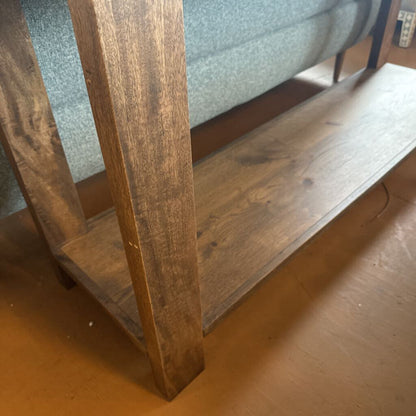Close-up of a wooden shelf corner with a gray cushioned chair in the background.