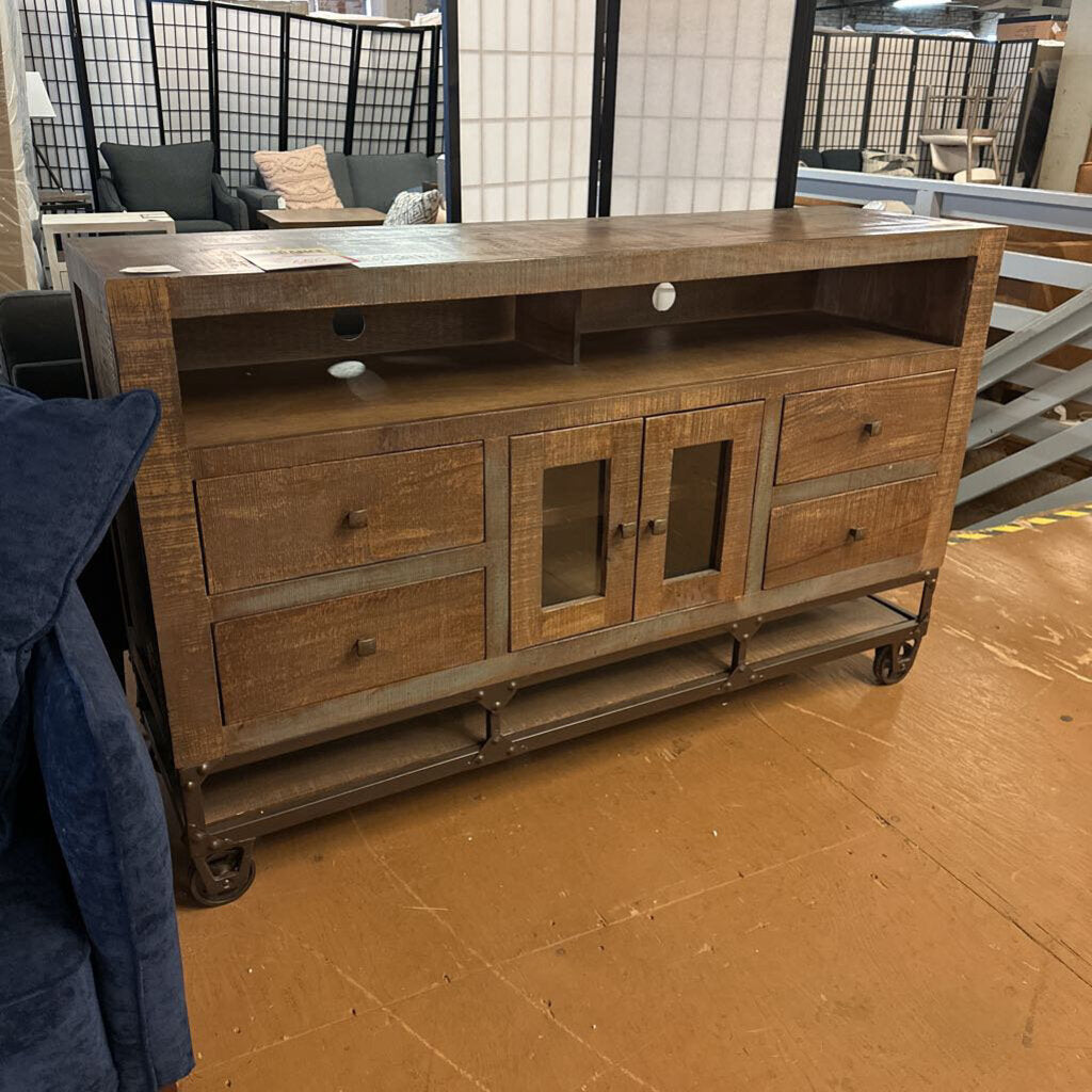 Wooden TV stand with glass doors and drawers in a room setting.