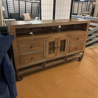 Wooden TV stand with glass doors and drawers in a room setting.