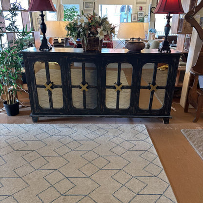 Decorative black console table with lamps and flowers in a living room setting.