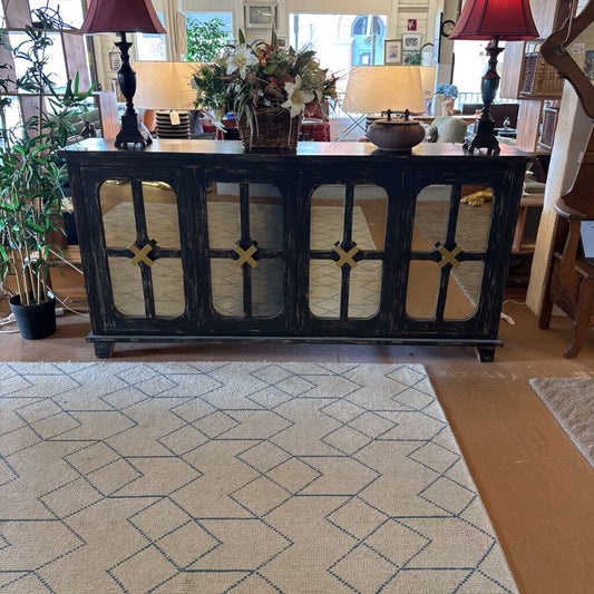 Decorative black console table with lamps and flowers in a living room setting.