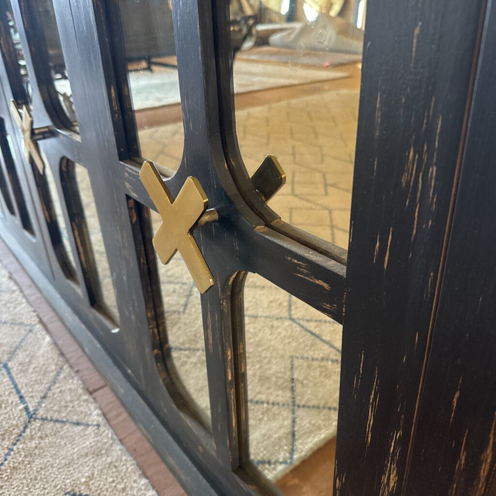 Close-up of a decorative metal gate with a gold emblem on a textured surface.