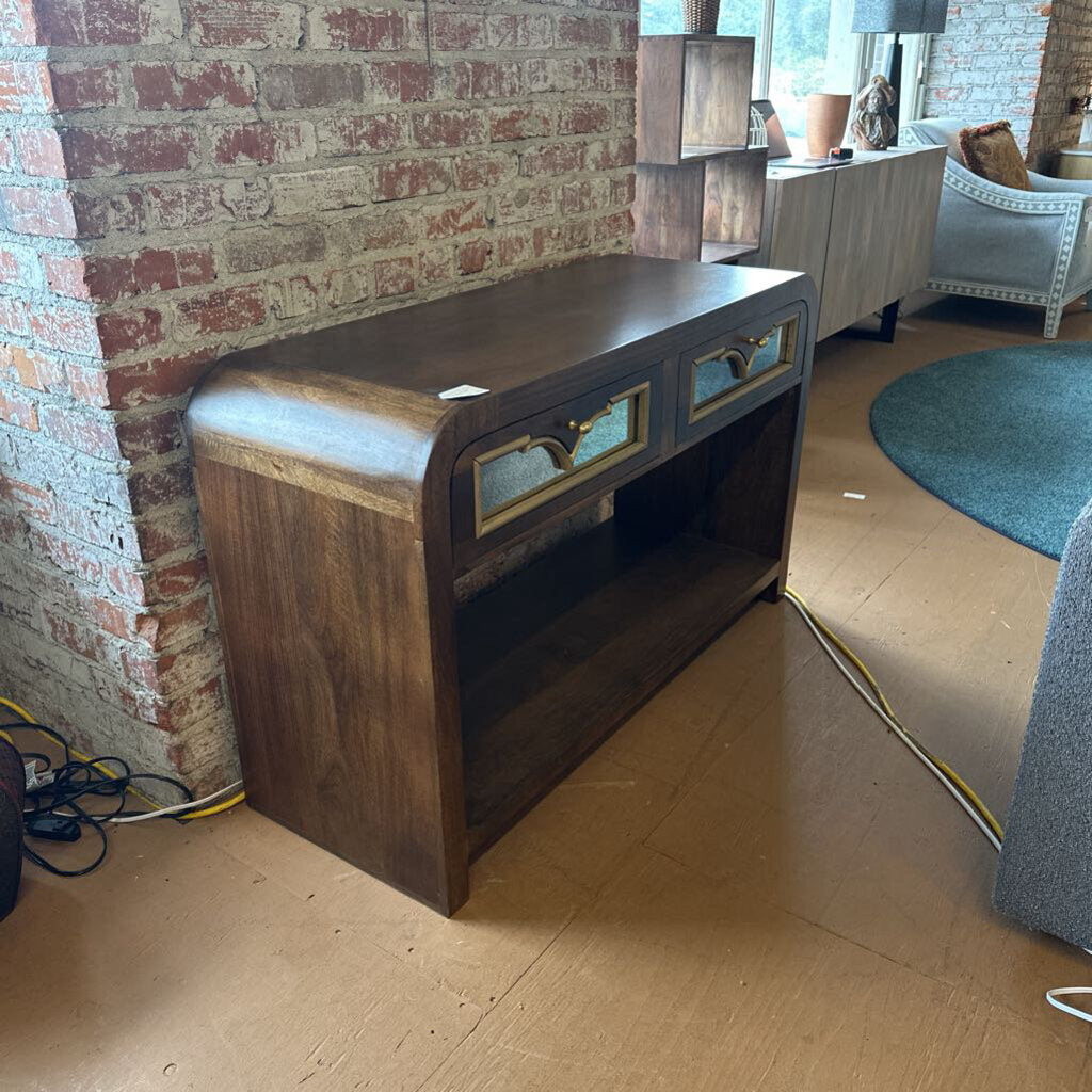 Wooden console table against a brick wall in a room with furniture and decor.