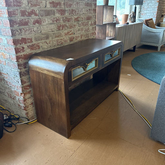 Wooden console table against a brick wall in a room with furniture and decor.