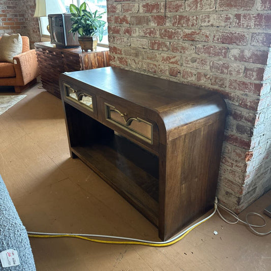 Wooden console table against a brick wall in a room with furniture and decor.