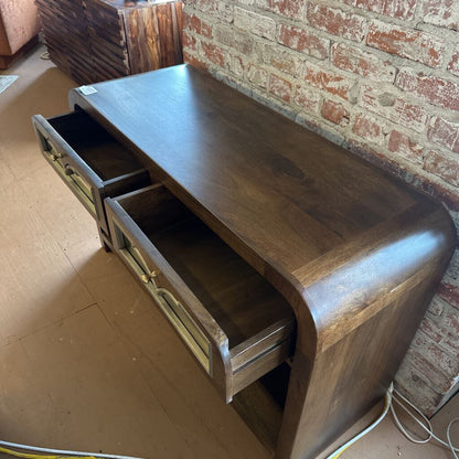 Wooden console table with drawers against a brick wall.