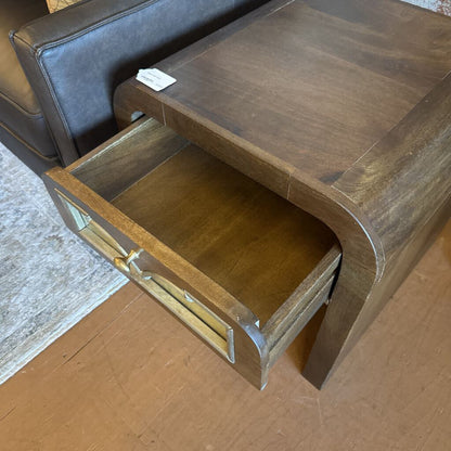 Wooden side table with an open drawer, showing wear and tear.