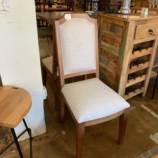 Wooden chair with beige cushioned seat and backrest in a casual dining setting.