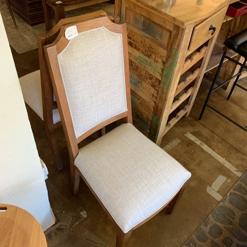 Wooden chair with beige cushioned seat and backrest in a rustic setting.