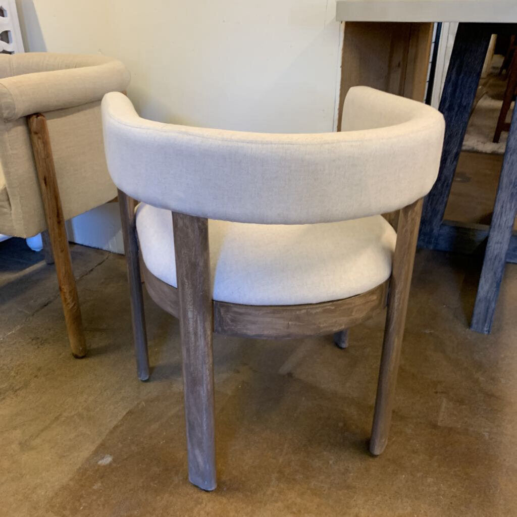 Chair with wooden legs and beige cushioned seat and backrest in a room setting.