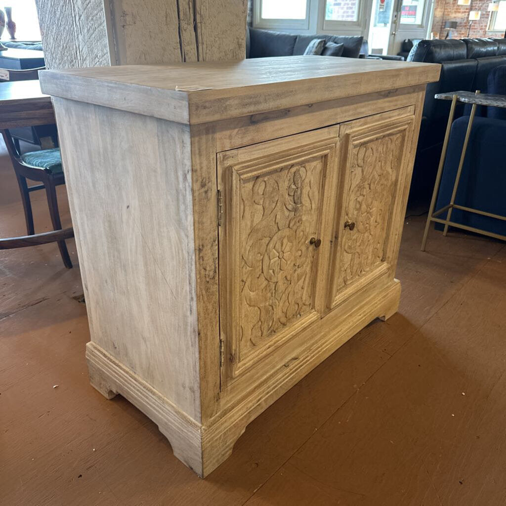Wooden cabinet with carvings in a room with furniture and decor.