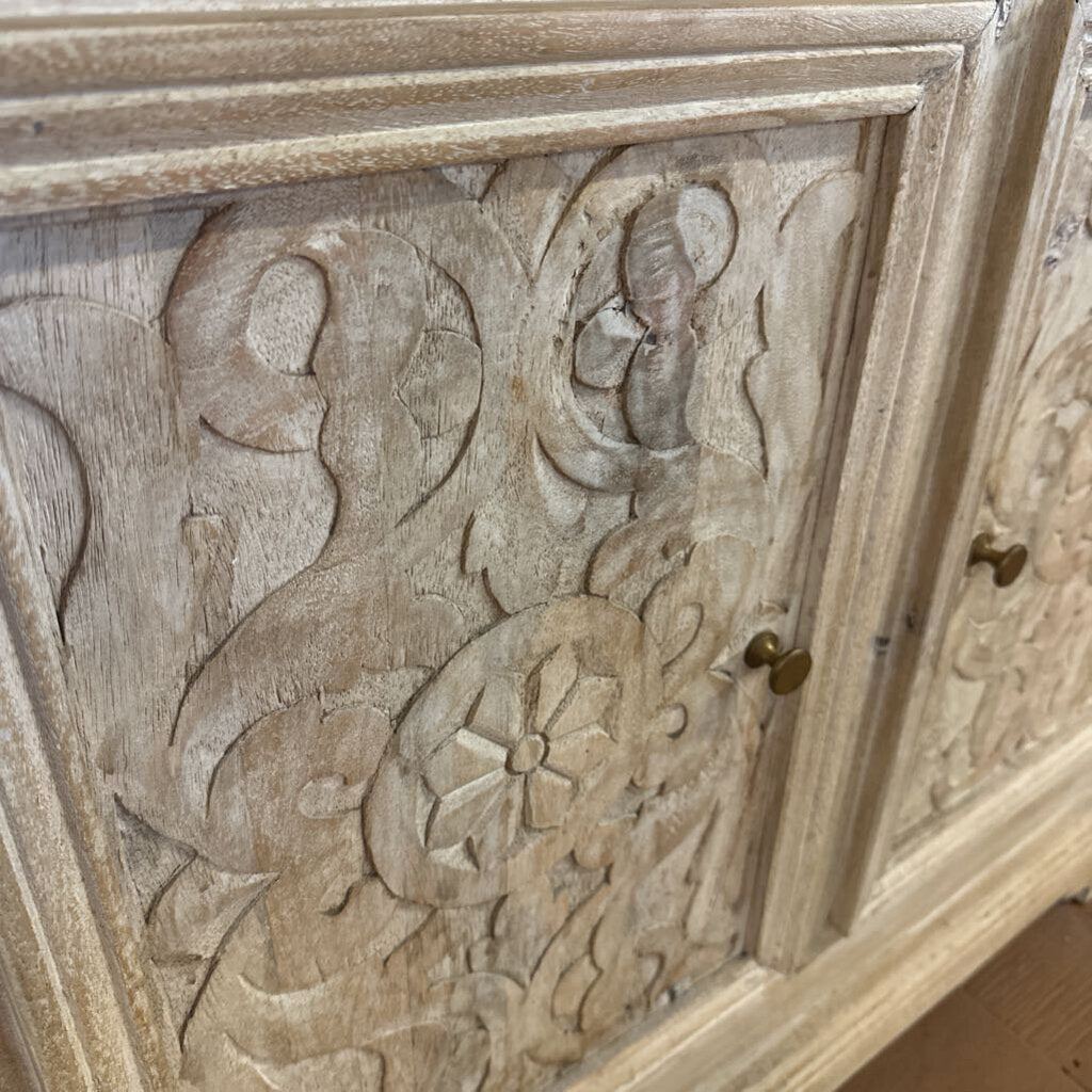 Wooden panel with intricate carvings and a small brass handle.