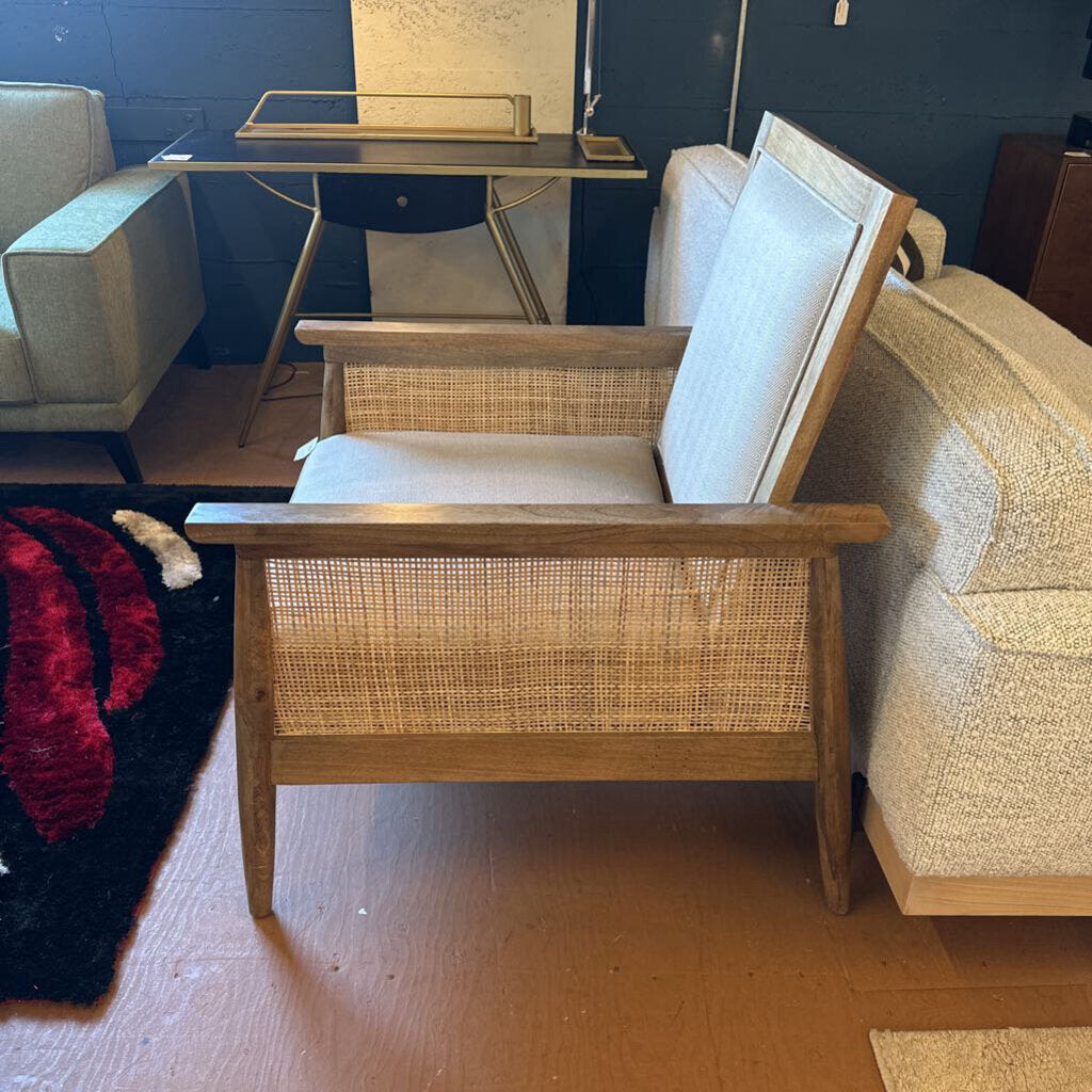 Wooden armchair with wicker backrest in a room with a blue wall and a rug.