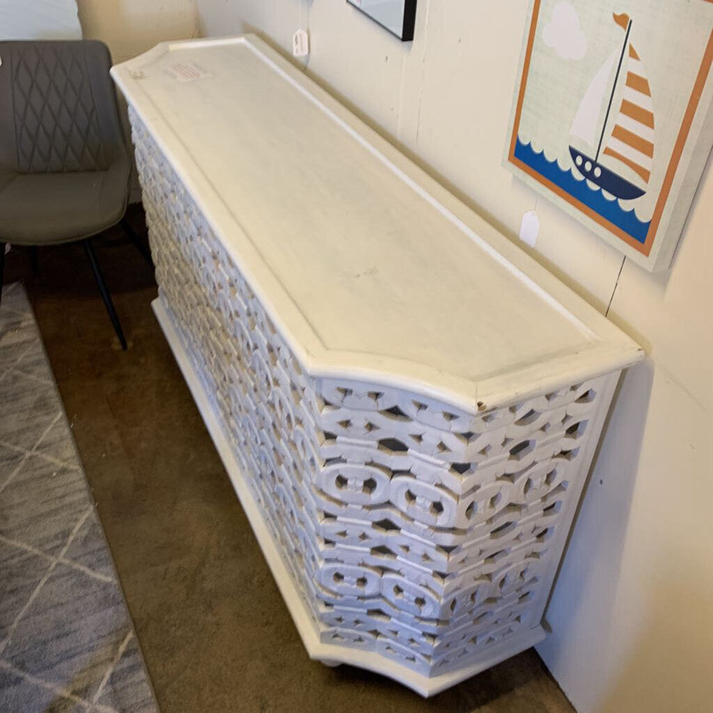 Decorative console table with intricate lattice design in a room setting.
