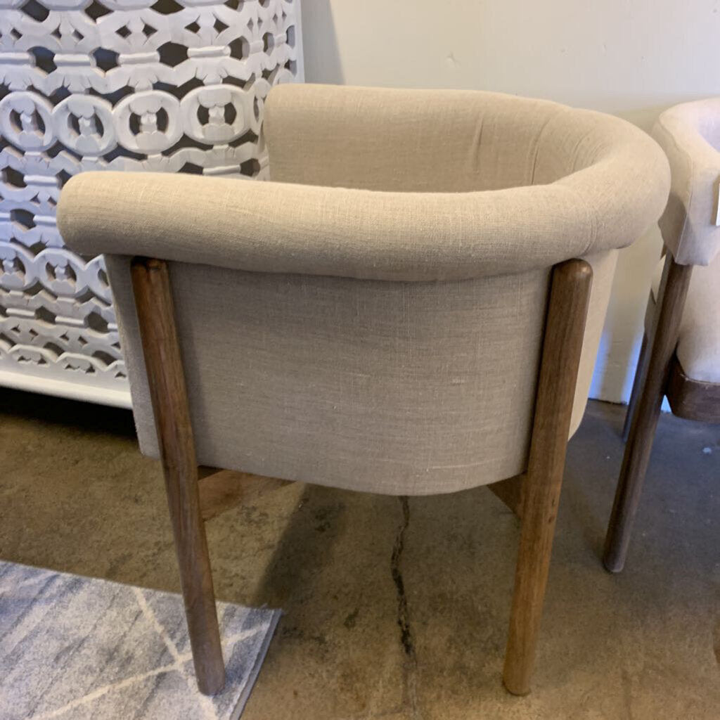 Beige upholstered chair with wooden legs on a patterned floor