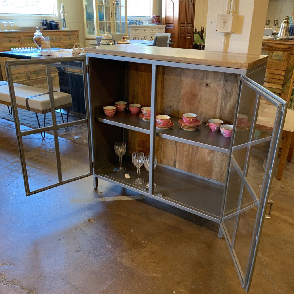 Wooden cabinet with glass doors in a room with furniture and decor.