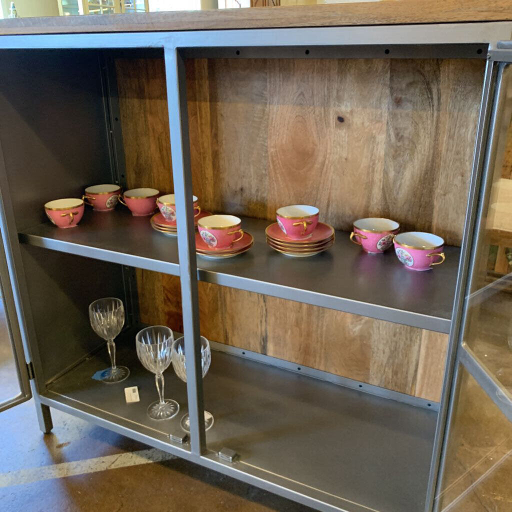 Metal shelving unit with pink teacups and glasses on a wooden floor.