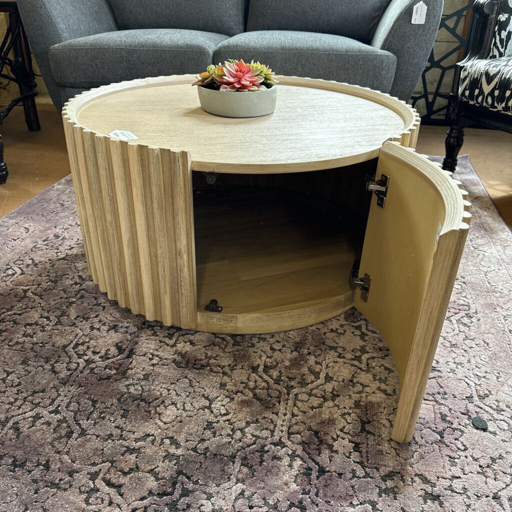 Round wooden coffee table with a hidden compartment on a patterned rug.