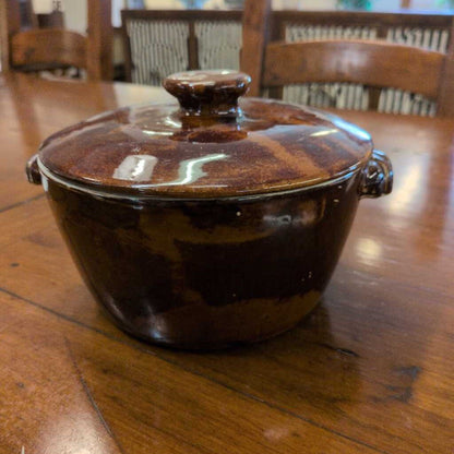 Brown ceramic pot with lid on a wooden table
