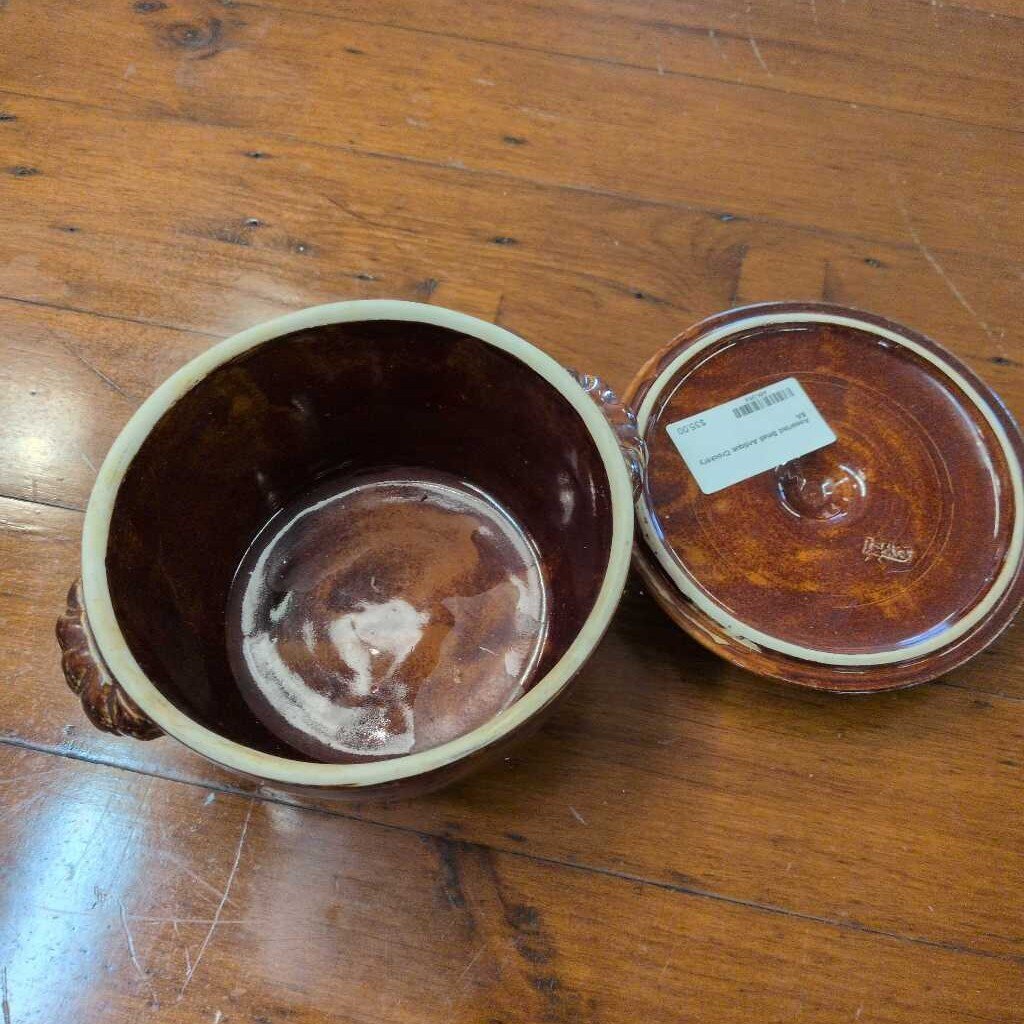 Brown ceramic container with lid on a wooden surface