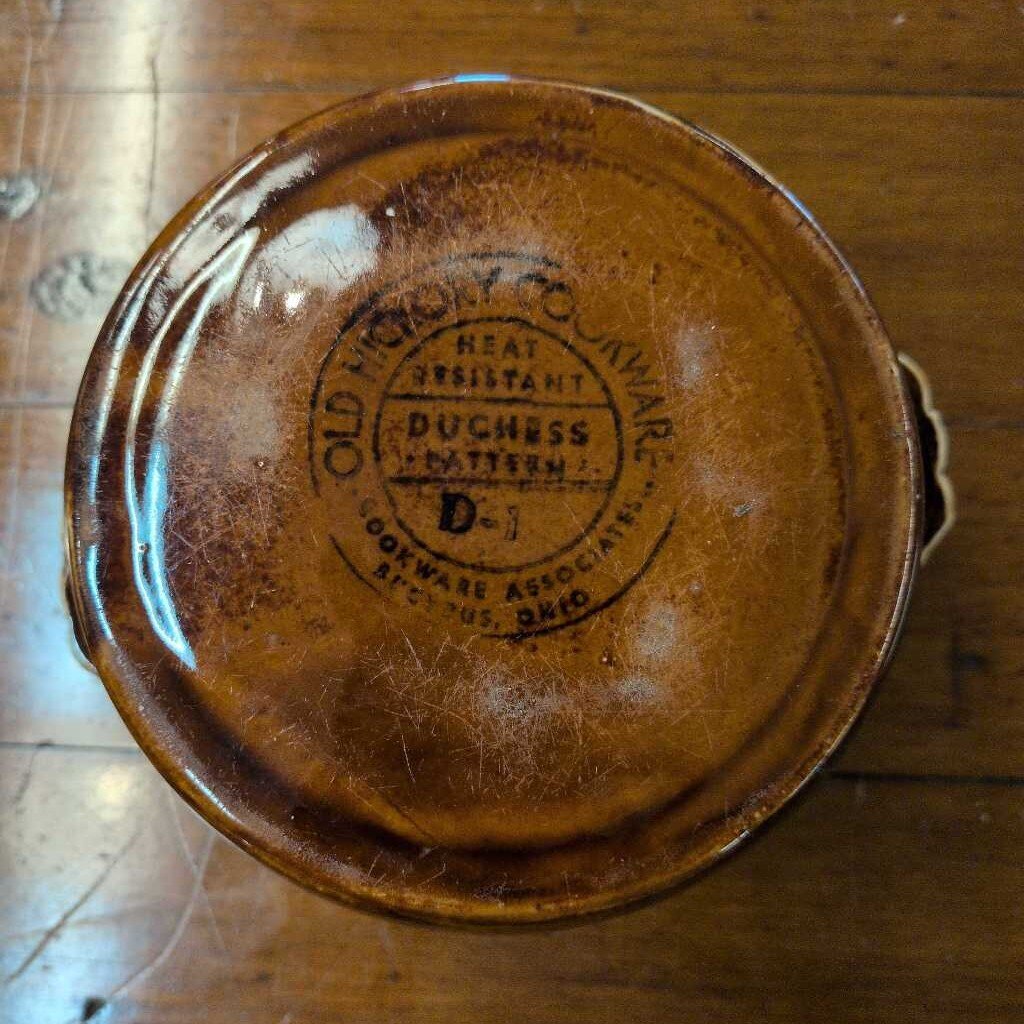 Brown ceramic dish with a visible brand logo on a wooden surface