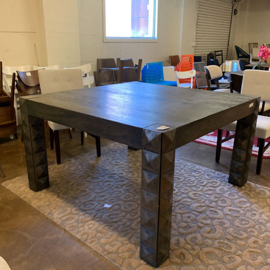 Dark wooden dining table in a showroom with chairs and other furniture.