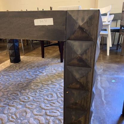 Dark metallic table leg with a textured design in an indoor setting
